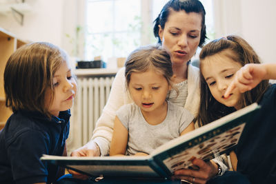 Teacher reading picture book for students in classroom at kindergarten