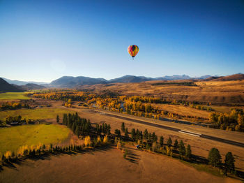 Hot air balloons flying over land against clear sky