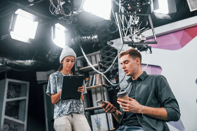 Young man is preparing for tv online broadcast. woman helps with make up.