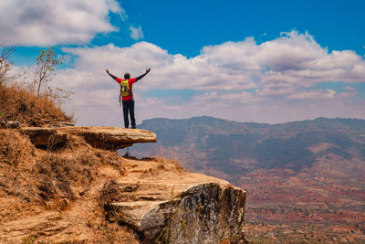 A hiker standing on a rock at a scenic lookout against valley and mountains in makueni county, kenya