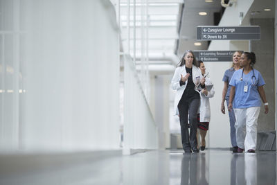 Female doctors discussing while walking in hospital corridor