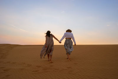 Woman standing on landscape at sunset