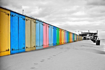 Multi colored huts on beach against sky