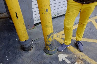 Low section of man standing on yellow umbrella