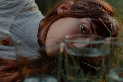 Close-up portrait of young woman lying on field