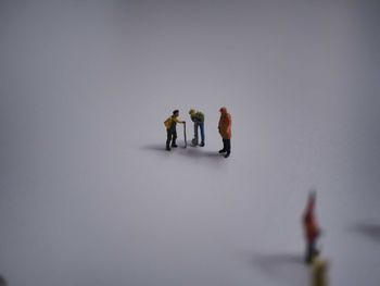High angle view of manual worker figurines on gray background