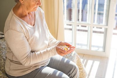 Midsection of senior woman holding medicines at home