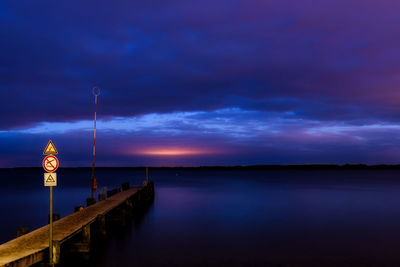 Pier over lake against sky at sunset