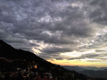 Silhouette city against dramatic sky at sunset