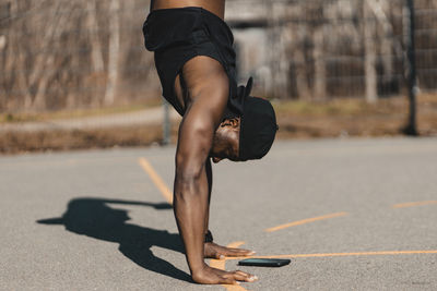 Man doing handstand over mobile phone on sports court