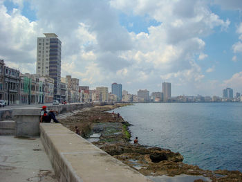 City buildings by sea against sky