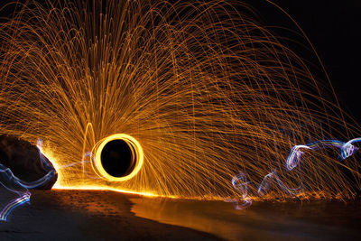 Blurred motion of burning wire wool on shore at night