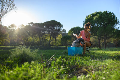 Distant view of middle-aged woman bathing her dog in the garden on a sunny day. pet care concept.