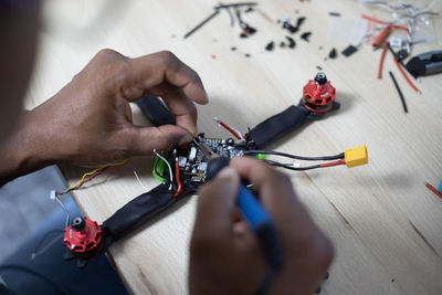 Cropped hands of man repairing quadcopter