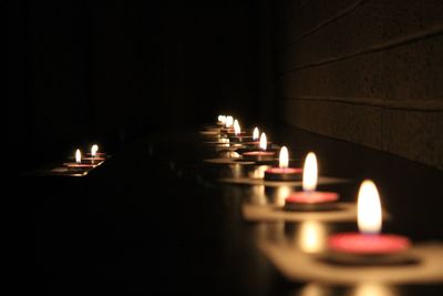 Close-up of illuminated tea lights in darkroom