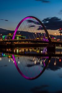 Illuminated bridge over river against sky at night