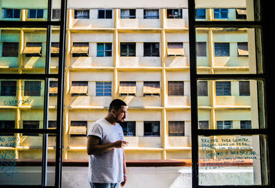 Full length of smiling young man standing against building in city