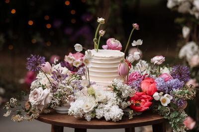 White wedding cake with fresh roses and wild flowers outdoors. wedding decoration table in the 