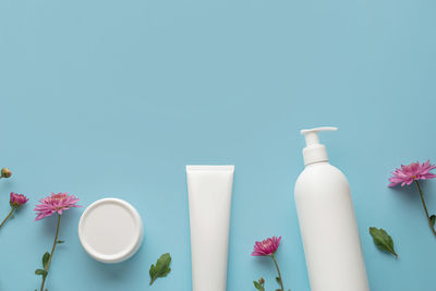 White tubes for cosmetics with pink gerberas on a blue background.