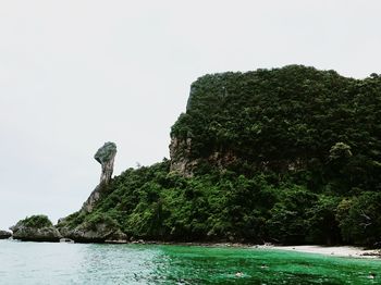 Rock formations by sea against clear sky