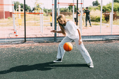 A teenage girl leads a basketball on a sports field, a girl protects the ball during a game