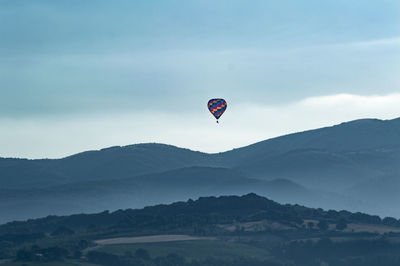 Hot air balloons flying in mountains against sky