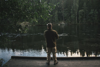 Rear view of man standing on pier by lake