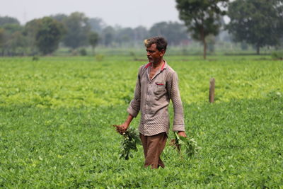 Full length of man standing in groundnut farm  field farming  background blur