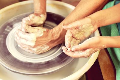 Close-up of people working on pottery wheel