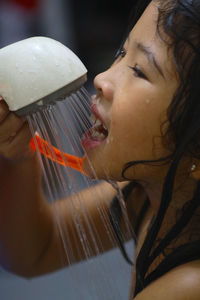 Close-up of girl taking bath with shower
