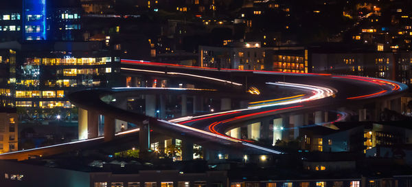 Illuminated bridge over river amidst buildings in city at night