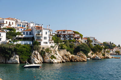 Sailboats in sea by buildings against clear sky