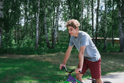 Teenager boy riding a bike in a park. curly teenager on a bicycle. active sport outdoors. 