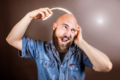 Man holding headphones against colored background
