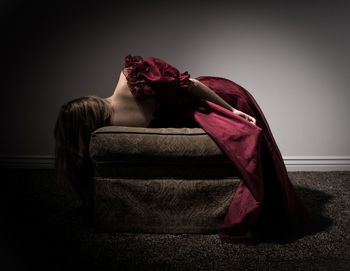 Rear view of woman lying on ottoman against wall