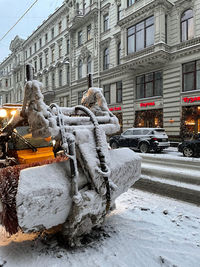 Statue by street against building in city during winter