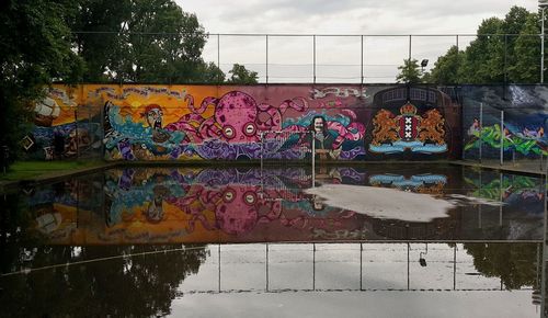 Graffiti on wall by trees against sky