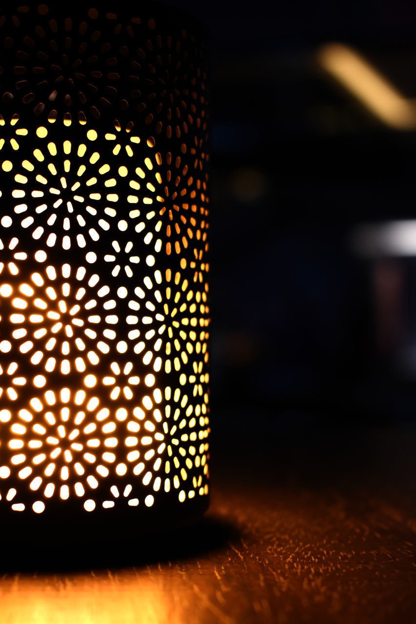 CLOSE-UP OF ILLUMINATED ELECTRIC LAMP ON TABLE IN DARK ROOM