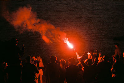 Crowd with red distress flare at night