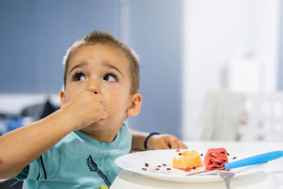 Close-up of boy eating fruits on table at home