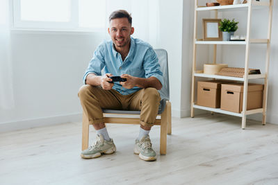 Portrait of young man sitting on hardwood floor at home