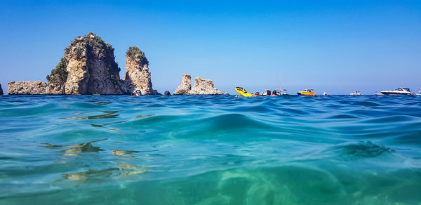 Panoramic view of rocks in sea against clear blue sky