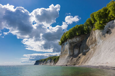 Scenic view of cliffs by sea against sky