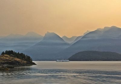 Scenic view of lake and mountains against sky during sunset