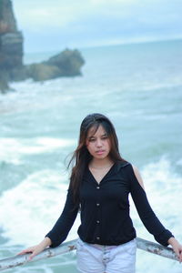 Young woman standing against sea