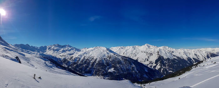 Scenic view of snowcapped mountains against blue sky