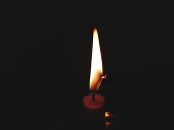 Close-up of lit candle in darkroom