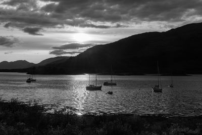 Sailboats in sea against mountains