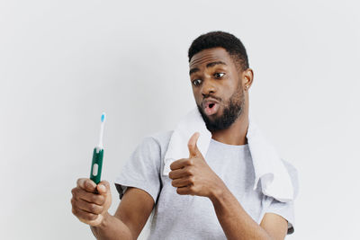 Portrait of young woman holding syringe against white background