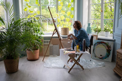 Artist with wine sitting near easel